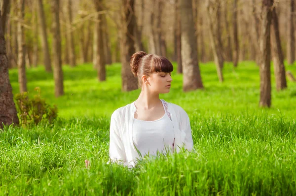 Jong meisje doet yoga op een groen gras — Stockfoto