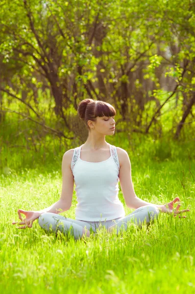 Yeşil çimenlerin üzerinde yoga yaparken genç kız — Stok fotoğraf