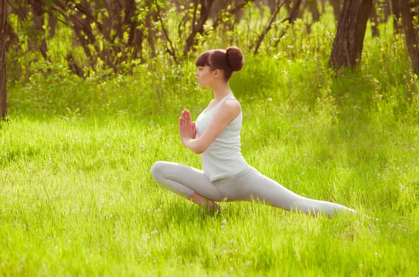 Yeşil çimenlerin üzerinde yoga yaparken genç kız — Stok fotoğraf
