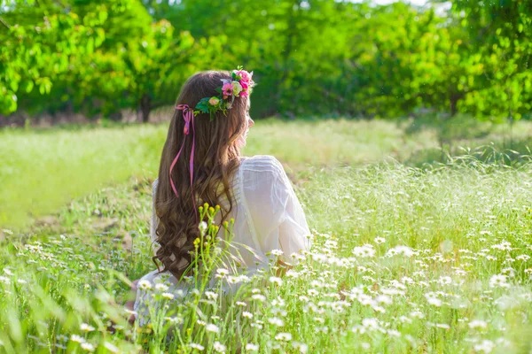 Дівчина з довгим волоссям в короні ромашок на полі — стокове фото
