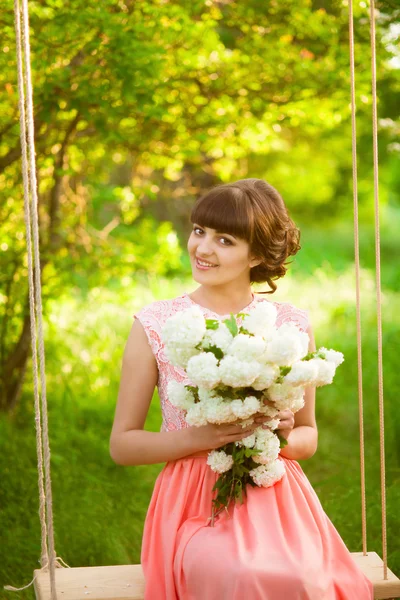 Mooi meisje in een lange jurk met de bloemen in de zomer — Stockfoto