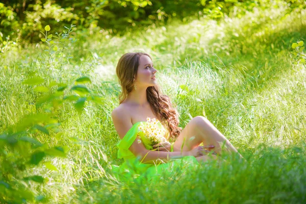 La jeune belle fille aux cheveux longs dans une robe lumineuse avec des marguerites — Photo