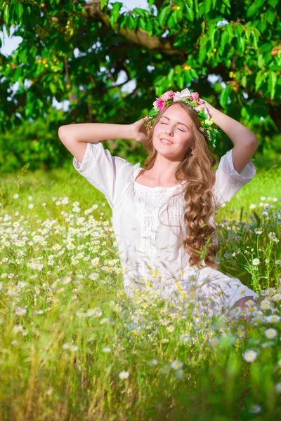 Flicka med långt hår på fältet med prästkragar — Stockfoto