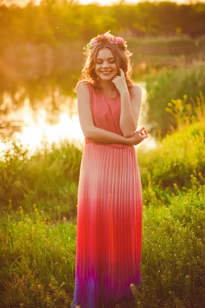 Young girl in a long dress  at sunset by the river in the summer — Stockfoto