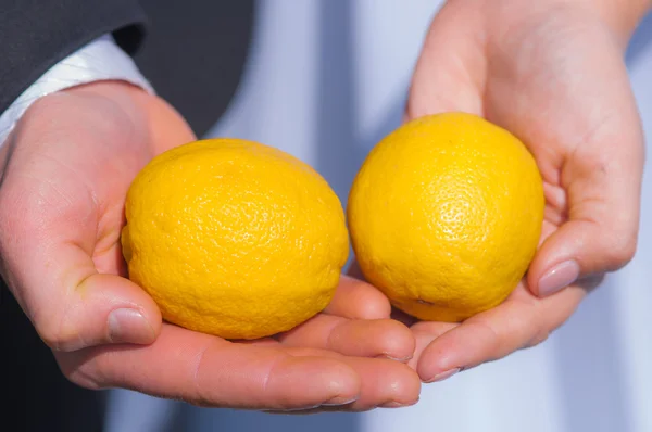 Mani degli sposi con un limone giallo — Foto Stock