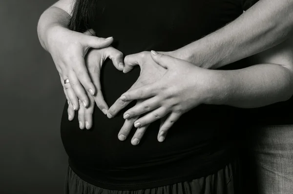 Hands of men and women on pregnant belly — Stock Photo, Image