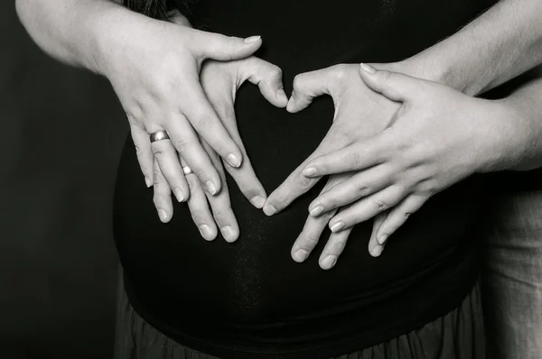 Händerna på män och kvinnor på gravid mage — Stockfoto