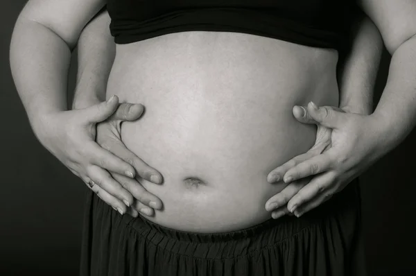 Händer män och kvinnor på gravid mage — Stockfoto