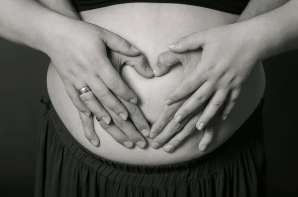 Handen mannen en vrouwen op zwangere buik — Stockfoto