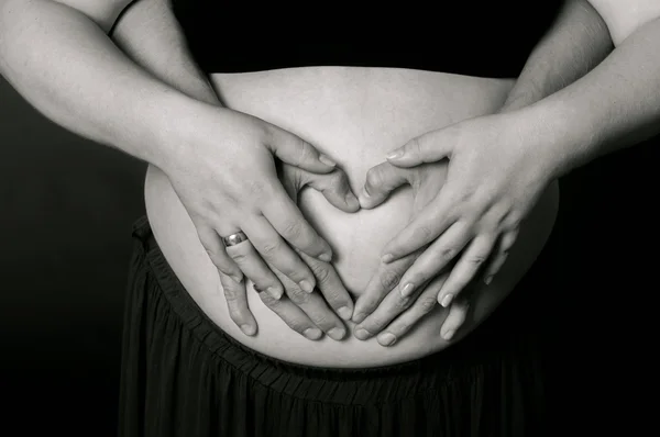 Handen mannen en vrouwen op zwangere buik — Stockfoto