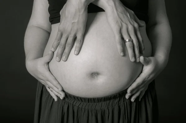 Руки мужчины и женщины на беременном животе — стоковое фото