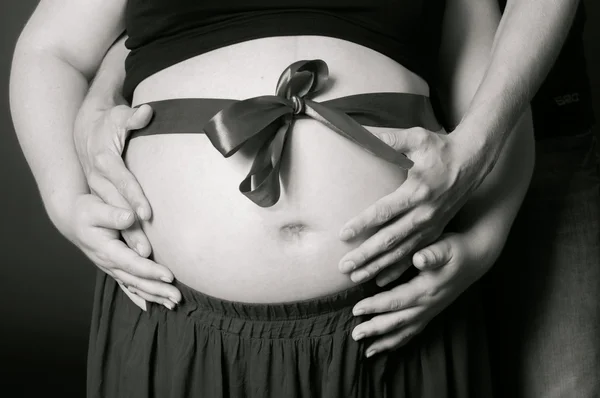 Handen mannen en vrouwen op zwangere buik — Stockfoto
