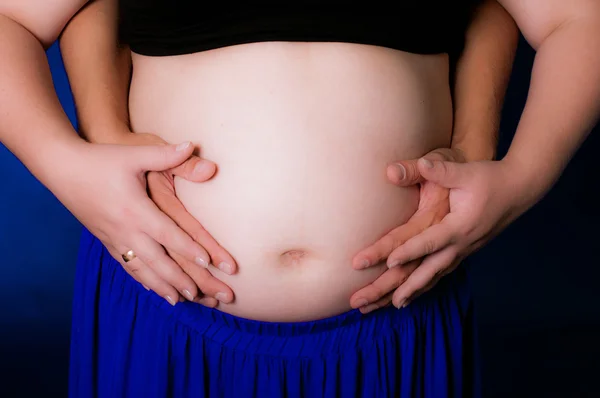 Mãos homens e mulheres na barriga grávida — Fotografia de Stock