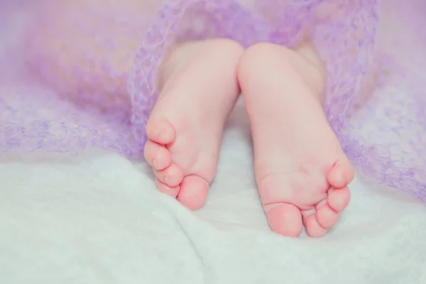 Pies bebé pequeño en una cama — Foto de Stock