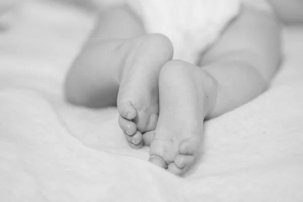 Pies bebé pequeño en una cama — Foto de Stock