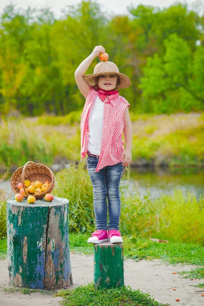 Petite fille en jean et chemise près d'une rivière aux pommes — Photo