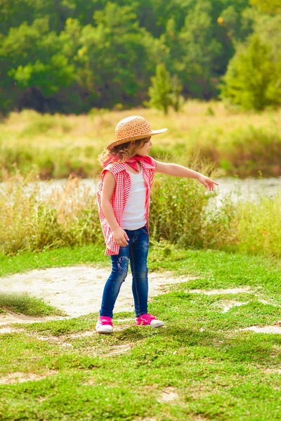 Bambina in jeans e camicia vicino a un fiume — Foto Stock