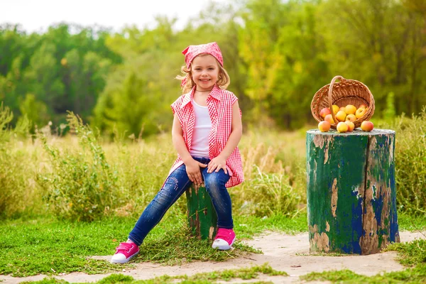 Little girl in jeans and a shirt near a river in autumn — Stock Photo, Image