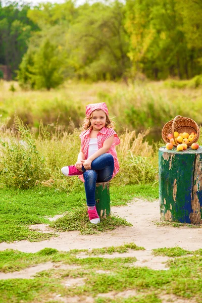 Bambina in jeans e camicia vicino a un fiume in autunno — Foto Stock