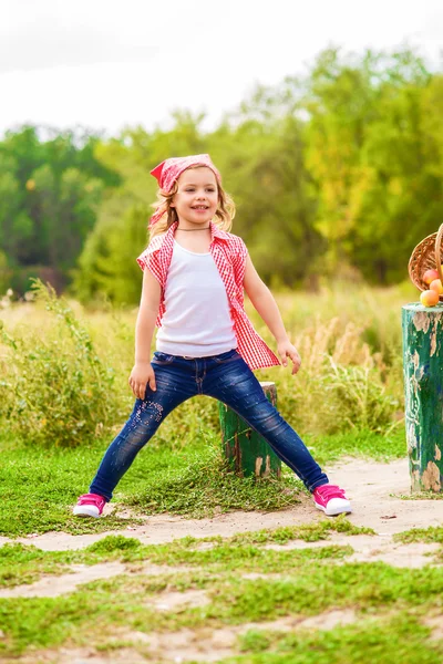 Malá holčička v džínách a košili, nedaleko řeky na podzim — Stock fotografie