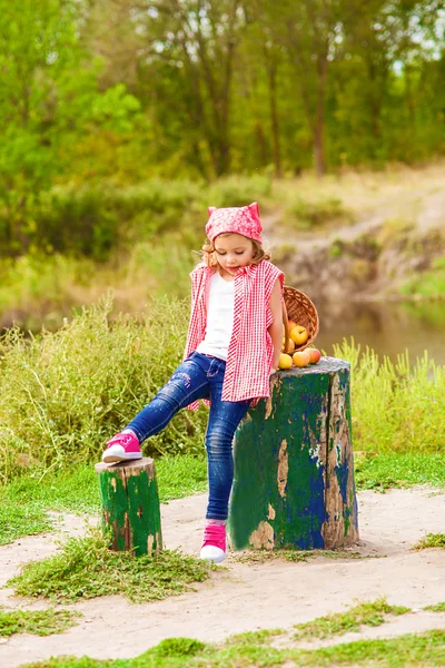 Bambina in jeans e camicia vicino a un fiume in autunno — Foto Stock