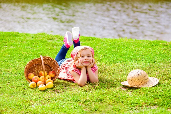 Little girl in jeans and a shirt near a river in autumn — Stock Photo, Image