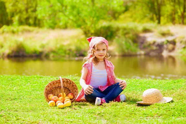 Little girl in jeans and a shirt near a river in autumn — Stock Photo, Image