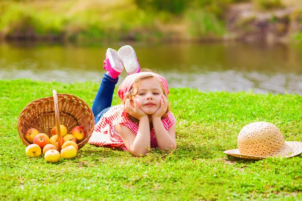 Little girl in jeans and a shirt near a river in autumn — Stock Photo, Image