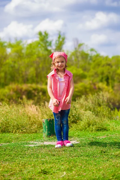 小女孩穿着牛仔裤和一件衬衫附近的一条河 — 图库照片