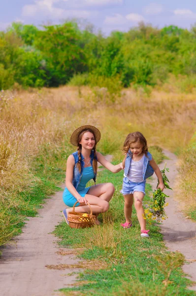 Chicas hermana en un campo con flores — Foto de Stock