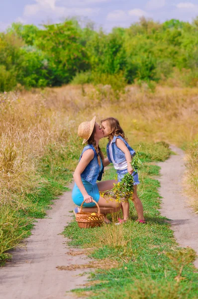 Chicas hermana en un campo con flores — Foto de Stock