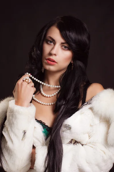 Beautiful girl with dark hair in a white fur coat — Stock Photo, Image