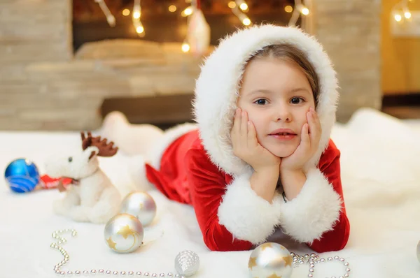 Malá holčička, oblečený jako Santa u krbu — Stock fotografie