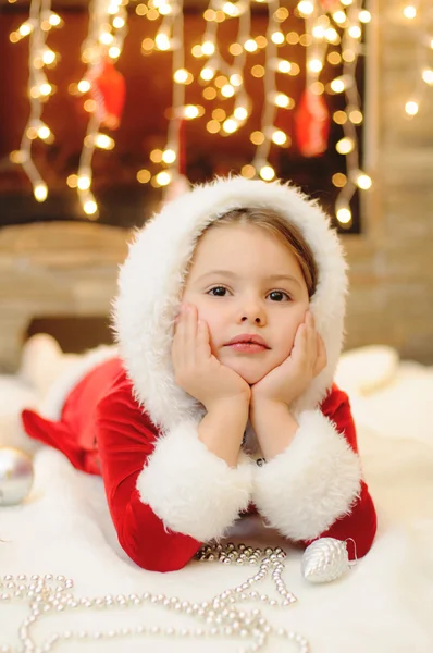 Little girl dressed as Santa by the fireplace — Stock Photo, Image