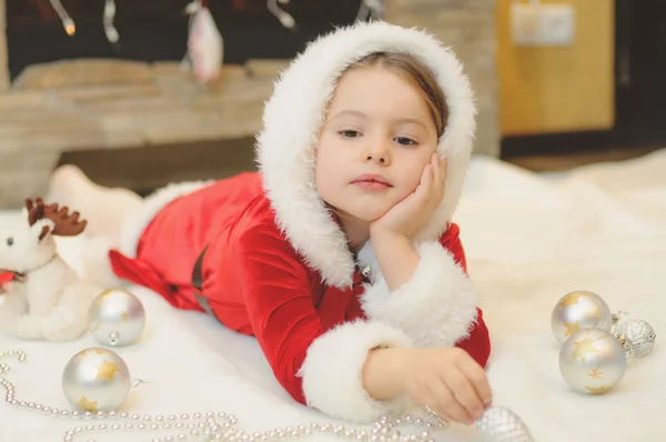 Menina vestida de Santa junto à lareira — Fotografia de Stock