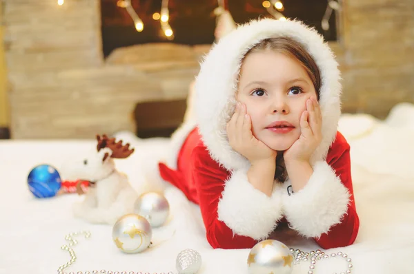 Liten flicka klädd som Santa vid brasan — Stockfoto