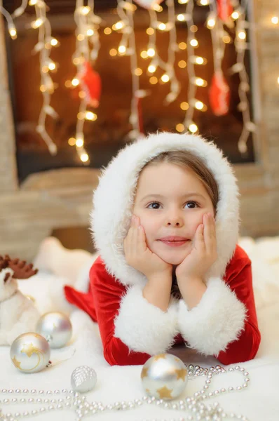 Bambina vestita da Babbo Natale vicino al camino — Foto Stock