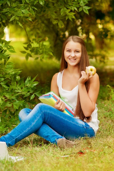 Kız öğrenci bir elma yemek kitapları ile — Stok fotoğraf