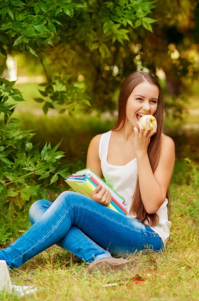 Kız öğrenci bir elma yemek kitapları ile — Stok fotoğraf