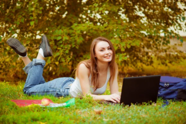 Öğrenci kız bilgisayarla çimenlerin üzerinde — Stok fotoğraf