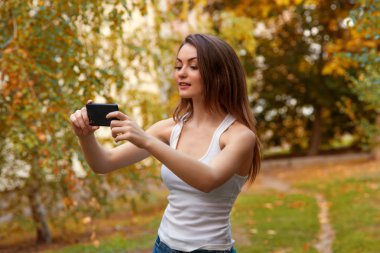 Cep telefonu ile parkta uzun saçlı genç kız