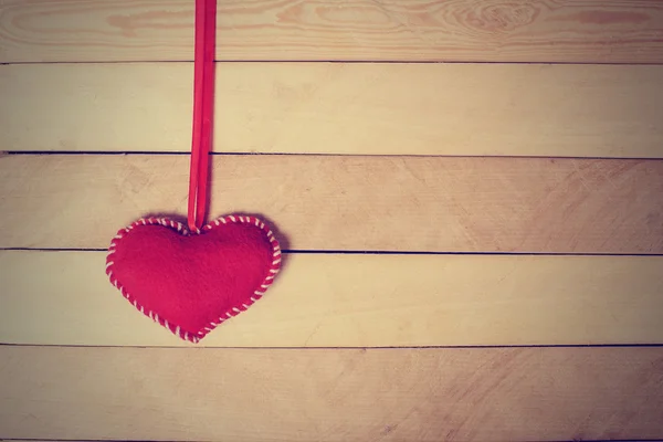 Textil corazón rojo en la cinta en una textura de madera —  Fotos de Stock