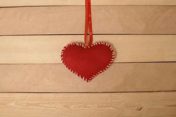 Textil corazón rojo en la cinta en una textura de madera —  Fotos de Stock