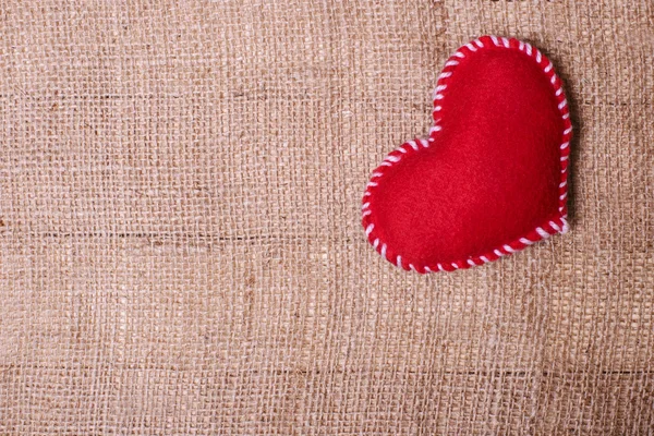 Textile heart on fabric texture of burlap — Stock Photo, Image