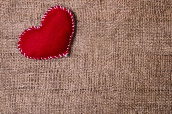 Textile heart on fabric texture of burlap — Stock Photo, Image