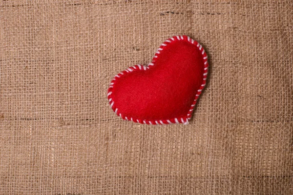 Textile heart on fabric texture of burlap — Stock Photo, Image