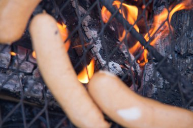 Kamp ateşi közlerinde sosisler ve alevler