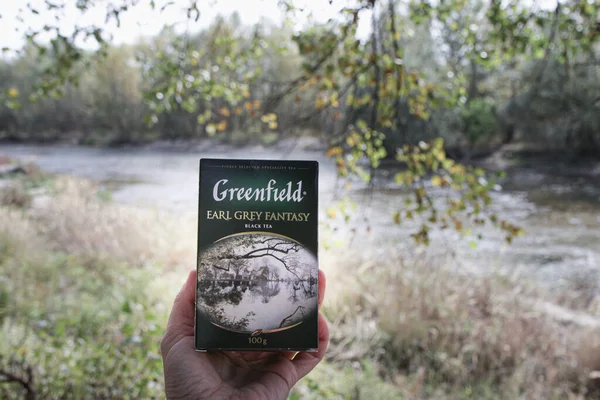 Pyatigorsk, Rusya, 01 Ekim 2020: Yeşil yaprakların ve nehrin arka planında bir paket Greenfield çayı