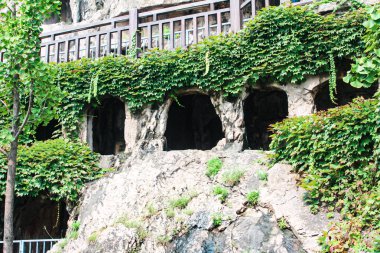 Luoyang, Çin, 3 Ağustos 2018: Kayaların görüntüsü ve Longmen Budist Mağara Tapınağı Kompleksi 'nde heykelleri olan mağaraların benzer açılışları