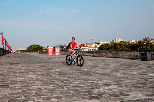Xi 'an, Çin, Ağustos 04, 2018: Güneş gözlüklü kadın turist Xi' an şehir duvarında bisiklet sürüyor